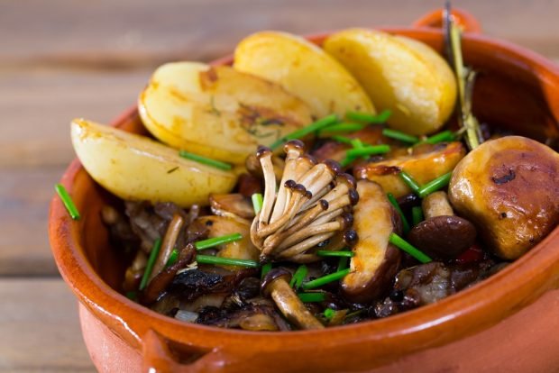 Young potatoes with forest mushrooms in pots